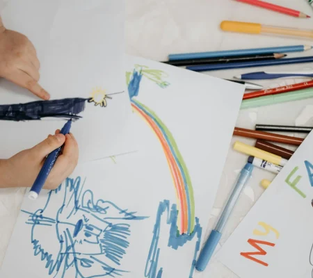 Children drawing with colorful markers on paper, depicting family and creativity.
